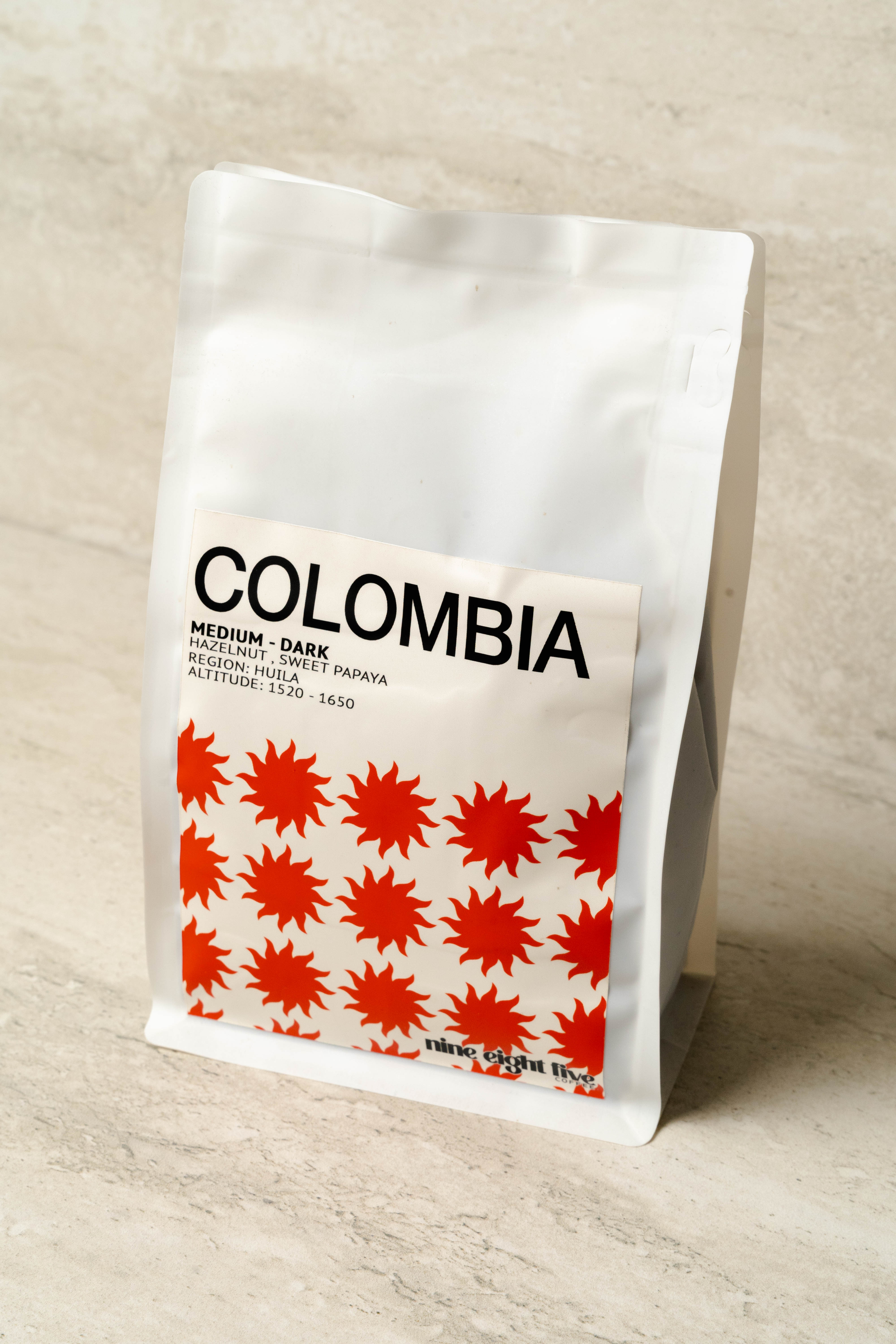 Coffee bag labeled 'Colombia' with red star pattern on a light wooden surface