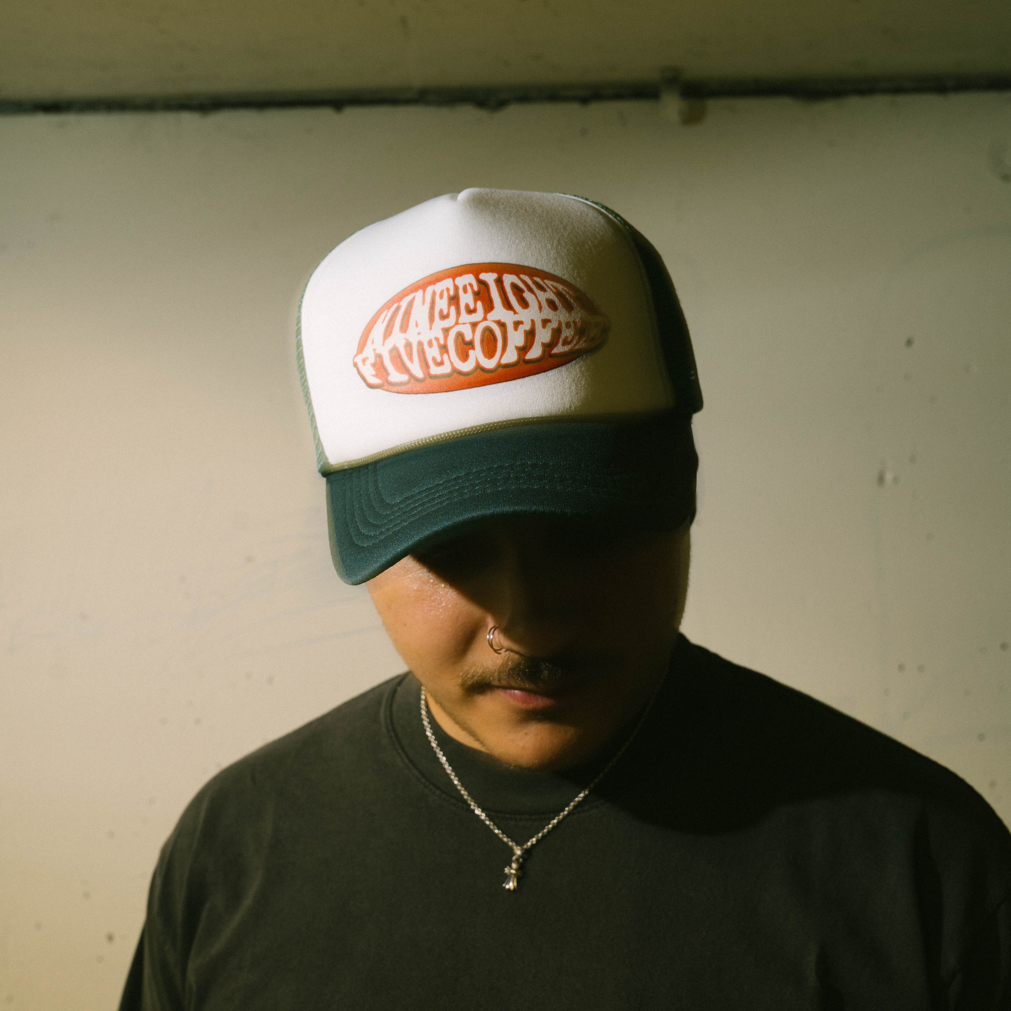 Person wearing a cap with 985 logo against a plain wall
