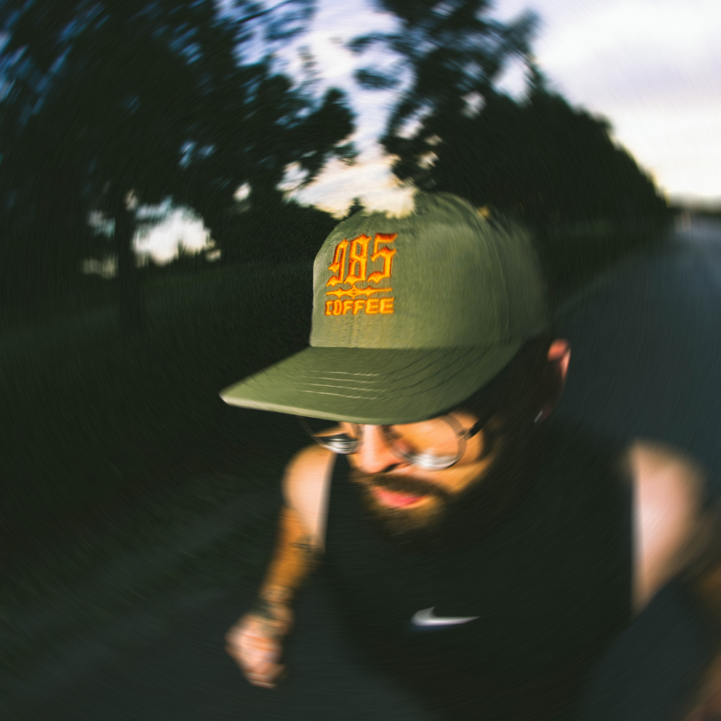Green camo nylon hat that says 985coffee and someone running on a track.